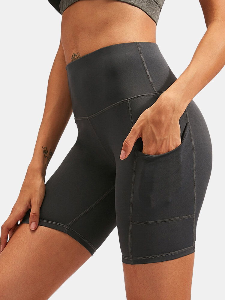 Pantalones cortos deportivos de color sólido de secado rápido Yoga para mujer con bolsillo lateral
